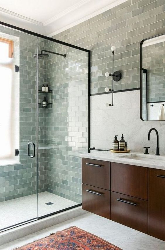 a farmhouse sage green bathroom clad with subway tiles, a dark-stained floating vanity and black fixtures