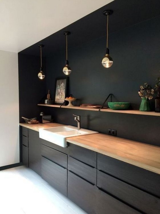 a minimalist black kitchen spruced up with a white sink and a wooden shelf plus countertops for a fresh look
