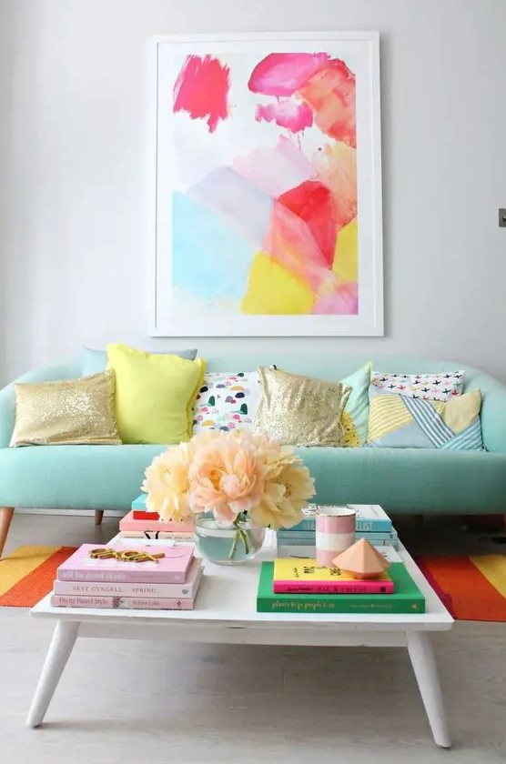 a mint sofa is a soft base for adding bright colors with the rug and the artwork for a cheerful feel