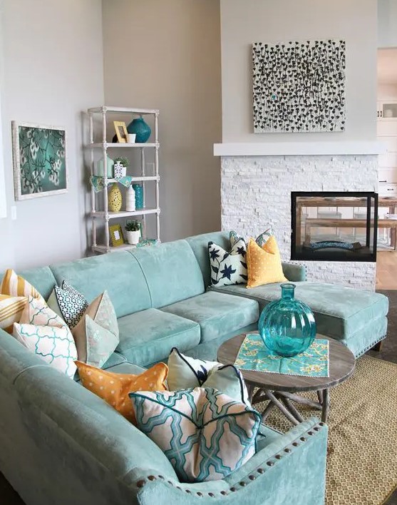 a neutral living room spruced up with a gorgeous mint blue sectional sofa and accessories for a seaside feel