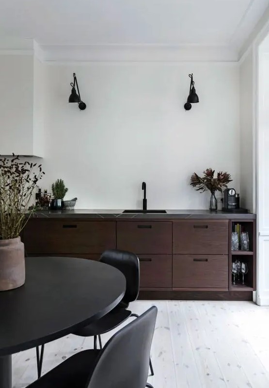 a bold walnut kitchen with dark cabinetry, a grey stone countertop and black fixtures and furniture