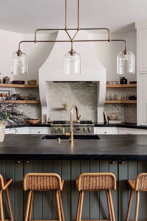 a beautiful famrhouse kitchen with white cabinets, a slate grey kitchen island, black soapstone countertops and open shelves