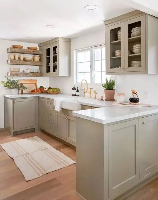 a beautiful greige kitchen with shaker cabinets, white stone countertops, glass cabinets, floating shelves and white stone countertops