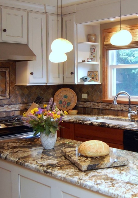 a beautiful kitchen with white and stained cabinets, a muted color tile backsplash and a white and gold granite countertops that bring interest