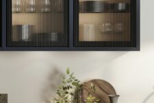 a beautiful matte black kitchen with flat panel and fluted glass upper cabinets plus butcherblock countertops is a chic space