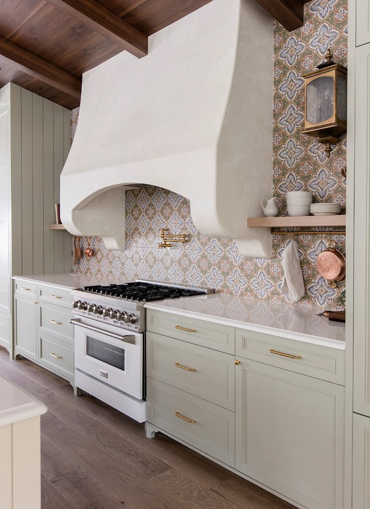 https://www.digsdigs.com/photos/2023/02/a-beautiful-modern-Mediterranean-kitchen-with-shaker-cabinets-in-sage-green-white-stone-countertops-and-a-bold-printed-tile-backsplash.jpg