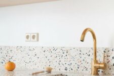 a blonde wood and white kitchen with a bright and fun terrazo countertop and a backsplash is a lovely space