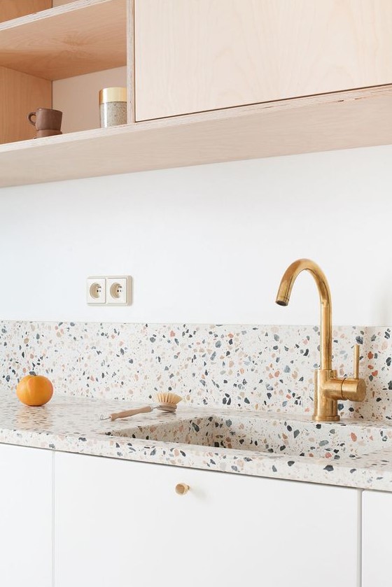 a blonde wood and white kitchen with a bright and fun terrazo countertop and a backsplash is a lovely space