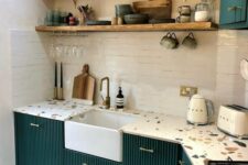 a bold dark green kitchen with fluted cabinets, a white tile backsplash and colorful terrazzo countertops and open shelves
