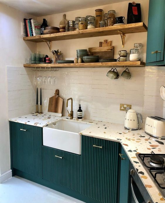 a bold dark green kitchen with fluted cabinets, a white tile backsplash and colorful terrazzo countertops and open shelves