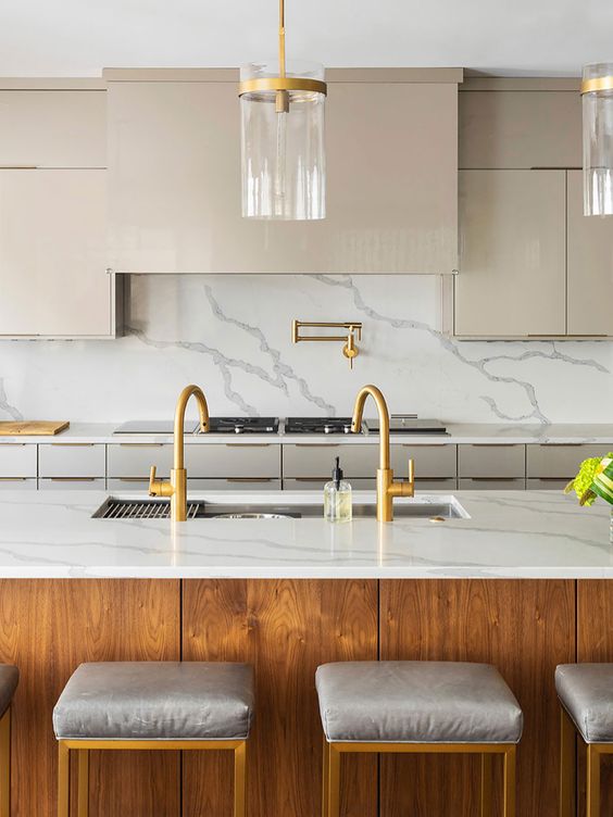 a chic and refined kitchen with tan cabinets, a white marble backsplash, a stained kitchen island and grey stools