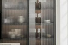 a chic contemporary kitchen with a taupe kitchen island, a large storage unit with fluted glass doors is a lovely and cool space