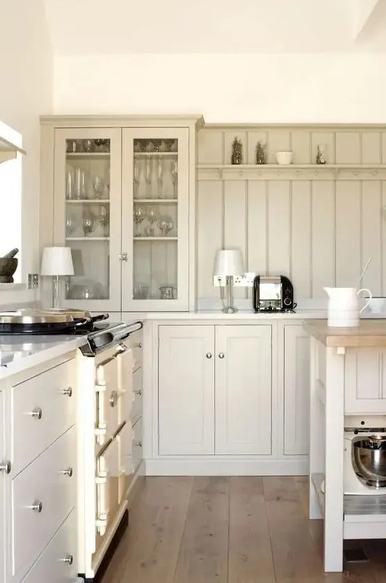 a chic cottage kitchen with tan shaker cabinets and a matching beadboard backsplash plus cool lamps is cozy and cool