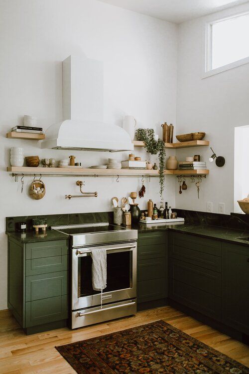 a chic dark green kitchen with black soapstone countertops, open shelving and a chic white hood is a lovely space with both a boho and farmhouse feel