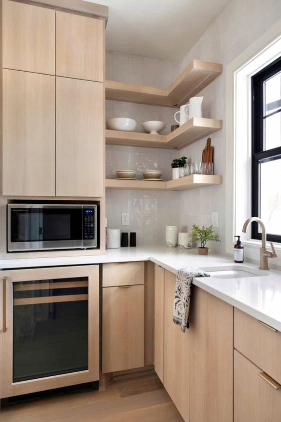 a chic light-stained kitchen with sleek flat panel cabinets, white stone countertops and a white glossy tile backsplash
