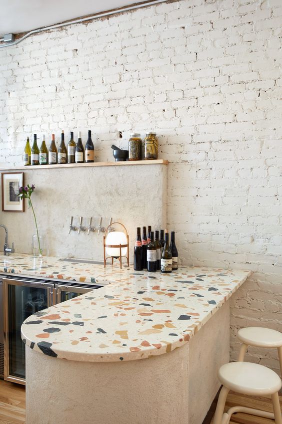 a chic modern kitchen with curved cabinets, colorful terrazzo countertops, a white stone backsplash is cool
