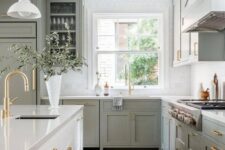 a classic sage green kitchen with shaker and glass front cabinets, a white stone countertop and square tiles, a creamy kitchen island