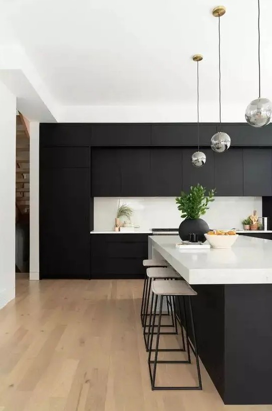 a contemporary black and white kitchen with matte cabinets, white countertops and a backsplash and bubble lamps