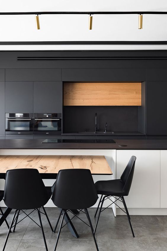 a contemporary kitchen with sleek black cabinets and a white kitchen island, black soapstone countertops, a table and black chairs