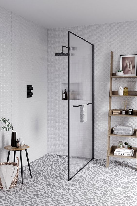 a contemporary neutral bathroom with printed tiles, a wooden ladder shelf, a fluted glass space divider and black fixtures