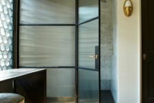 a contemporary refined bathroom with a shower space with fluted glass doors with black framing is a very chic and exquisite one