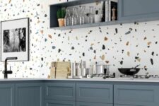 a cool kitchen with slate blue cabinets, a white terrazzo backsplash, floor and countertops and black fixtures