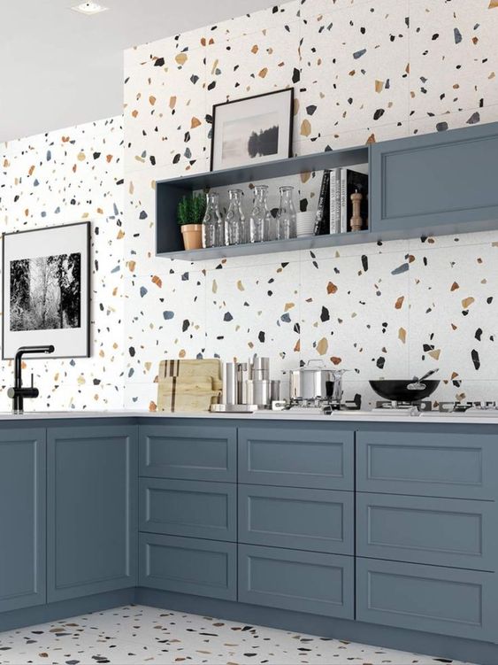 a cool kitchen with slate blue cabinets, a white terrazzo backsplash, floor and countertops and black fixtures