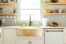 a cool white modern kitchen with black and white terrazzo countertops and a backsplash plus touches of gold