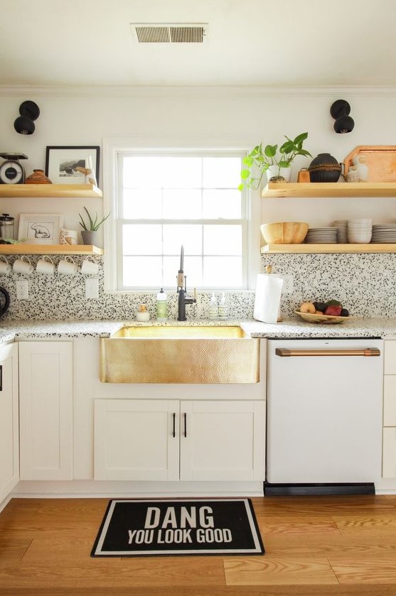 a cool white modern kitchen with black and white terrazzo countertops and a backsplash plus touches of gold