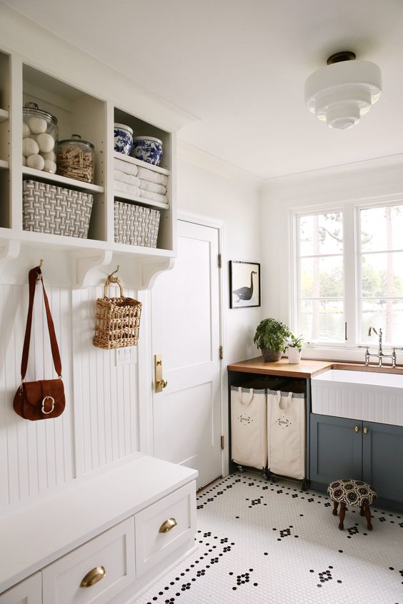 a cozy laundry mudroom with a beadboard rack with drawers and open storage, a grey cabinet and a sink plus a penny tile floor