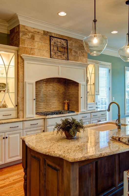 a creamy kitchen with shaker cabinets, a cooker with a built-in hood, a stained kitchen island and neutral granite countertops