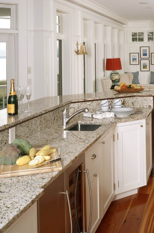 a creamy kitchen with shaker cabinets and grey granite countertops plus built-in appliances and stainless steel fixtures
