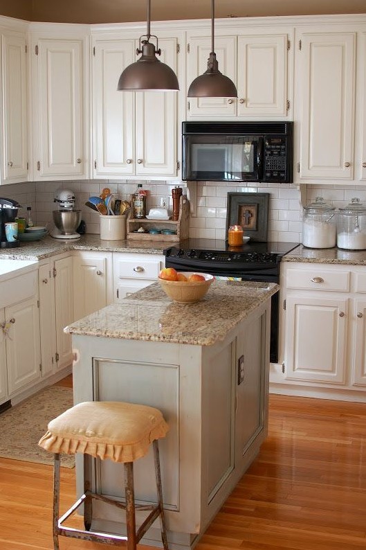 a creamy vintage kitchen with granite countertops, metal pendant lamps and metal stools looks cozy and stylish
