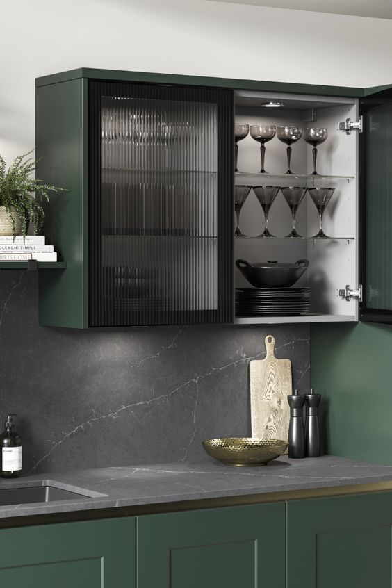 a dark green kitchen with shaker cabients and black fluted glass cabinets, a black marble backsplash and countertops is a chic and refined space