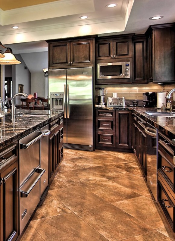 a dark-stained kitchen with shaker cabinets, a grey tile backsplash and black and gold granite countertops