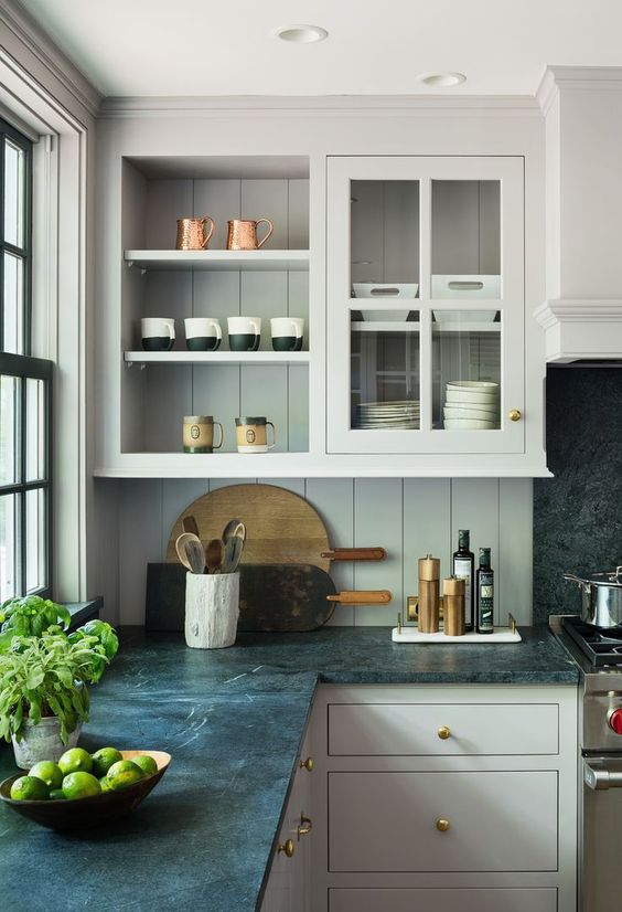 a dove grey kitchen with flat panel and glass front cabinets, a beadboard backsplash and black soapstone countertops