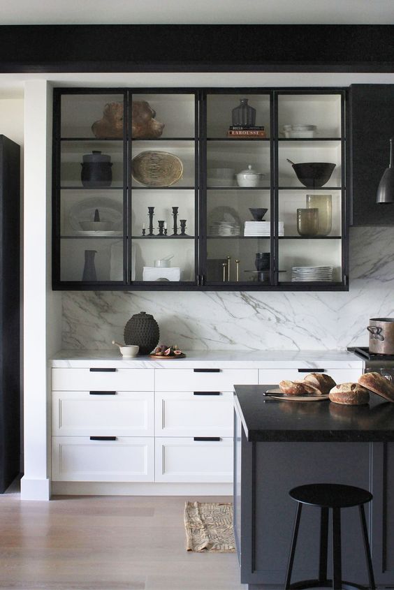 خزائن مطبخ زجاجية A-dramatic-black-and-white-kitchen-with-shaker-adn-glass-cabinets-a-white-kitchen-island-with-a-black-countertop-a-white-backsplash