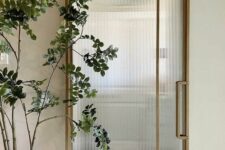 a gold barn door with fluted glass is a fresh take on a usual barn door that looks more lightweight and beautiful