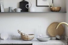 a graphite grey kitchen with light grey terrazzo countertops and a long shelf instead of upper cabinets for an airy feel in the space