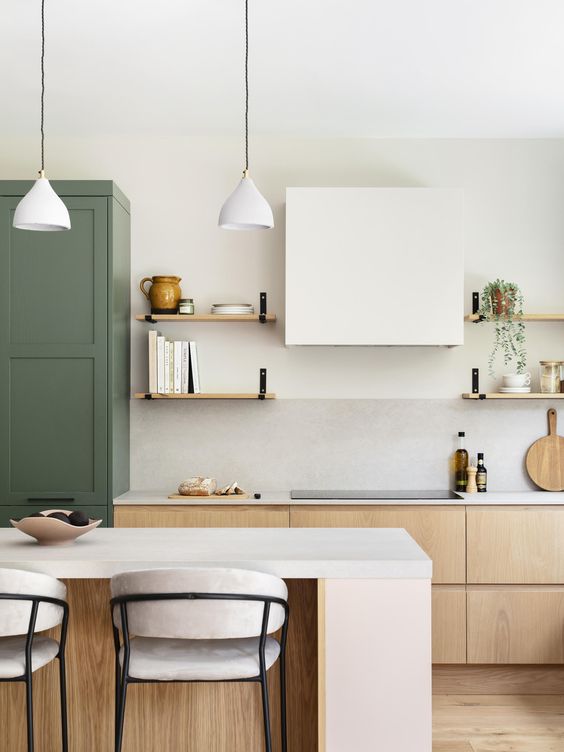 a green and light-stained kitchen with flat panel and shaker style cabinets, open shelves, a large kitchen island and a white hood