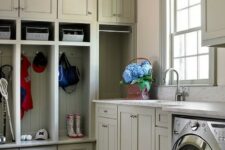 a greige mudroom laundry with shaker cabinets and an open storage unit, a washing machine and a dryer and white stone countertops