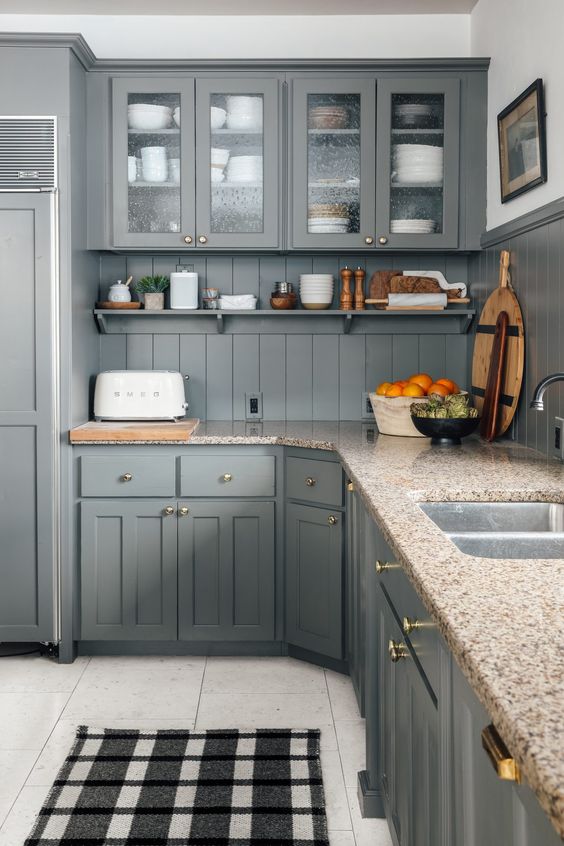 a grey farmhouse kitchen with shaker cabinets, glass ones and open shelves and beige granite countertops is lovely