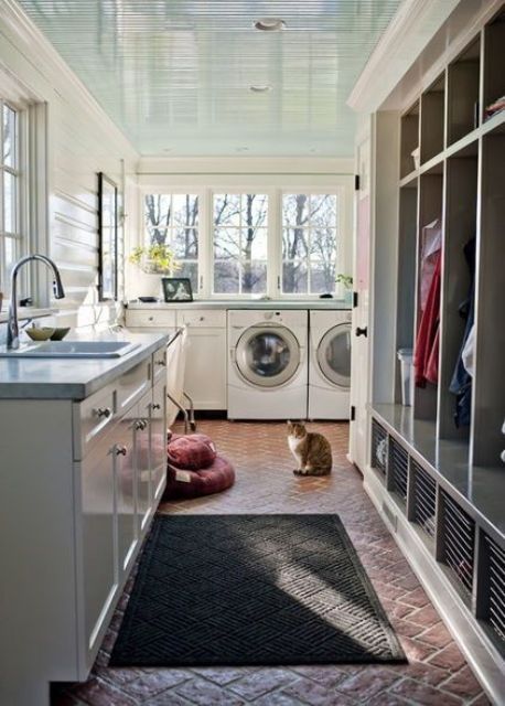 a large laundry mudroom with an open rack, shaker cabinets, a washing machine and a dryer and a printed rug