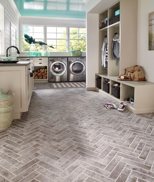 a large mudroom laundry with neutral cabinetry, a washing machine and a dryer, large windows and a parquet floor