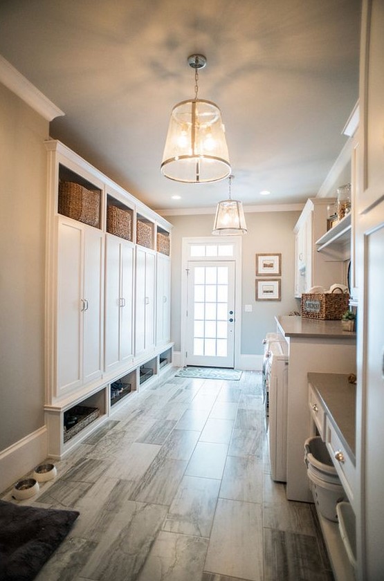 a large neutral mudroom laundry with large storage cabinets, baskets, a washing machine and a dryer and some open storage shelves