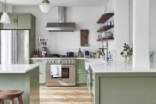 a large sage green kitchen with shaker cabinets, white stone countertops, open shelving and wooden stools is elegant and cool
