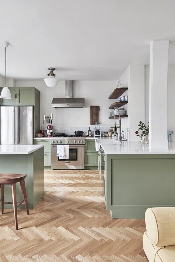 a large sage green kitchen with shaker cabinets, white stone countertops, open shelving and wooden stools is elegant and cool