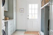 a light blue mudroom laundry with shaker cabinets, an open storage unit, baskets and printed rugs, a washing machine and a dryer