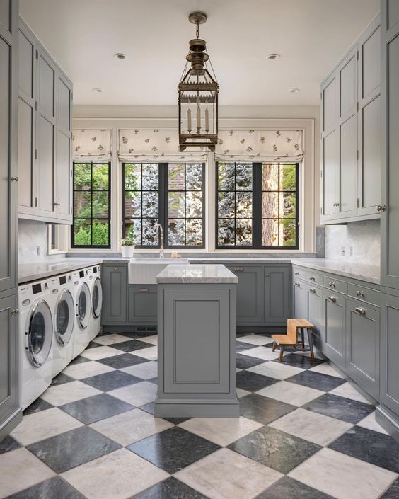 a light grey farmhouse mudroom laundry with shaker cabinets, a checked floor, printed curtains and a pendant lamp