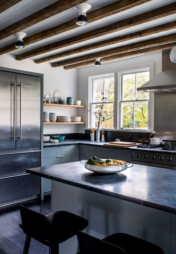 a light grey kitchen with flat panel cabinets and a kitchen island, black soapstone countertops, wooden beams and open shelves